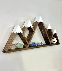 a wooden shelf with mountains, rocks and a soccer ball on it