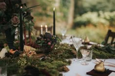 the table is set with candles, flowers and other items for an outdoor dinner party