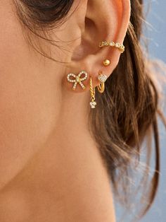 a close up of a woman's ear wearing gold and diamond earrings with the word love written on it