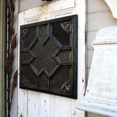 an old door with a decorative panel hanging on it's side wall next to a lamp