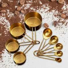 gold measuring spoons with monogrammed initials on them and coffee beans in the background