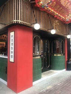 the entrance to a chinese restaurant with red and green walls, decorated with lights and decorations