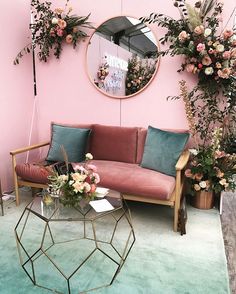 a living room filled with furniture and flowers on the wall next to a round mirror