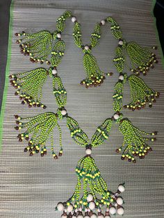 green and white beaded necklaces on a gray tablecloth with beads in the shape of leaves