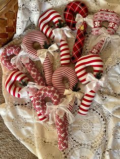 several red and white candy canes laid out on a lace doily with bows