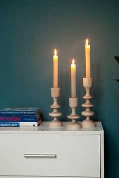 three lit candles on top of a white dresser