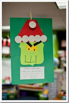 a paper cut out of a green monster with a santa hat hanging from it's side