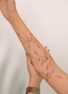 a woman's arm with flowers on it and her hand holding something in the air