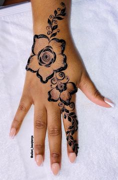 a woman's hand with black hennap and flowers on the top of it