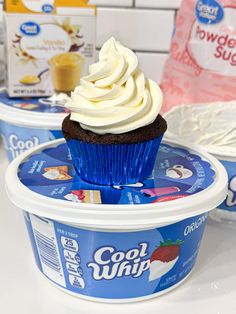 cupcakes with frosting and yogurt are on top of ice cream containers