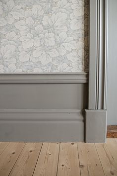 an empty room with wood floors and a wall papered in flower pattern on the wall