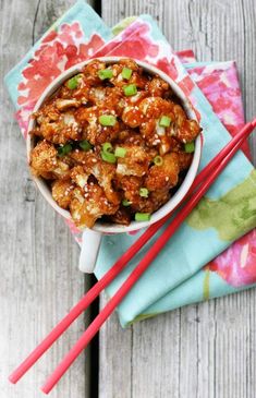 two red chopsticks sitting next to a bowl of food on top of a table