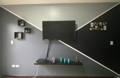 a flat screen tv mounted to the side of a wall next to a shelf with cups on it