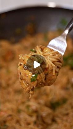 a spoon full of noodles and vegetables being held by someone