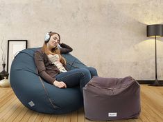 a woman is sitting on a bean bag chair and listening to music with headphones