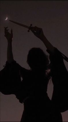 the silhouette of two people reaching up to grab an object with their hands