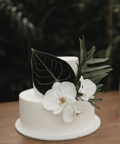 a wedding cake with white flowers and green leaves