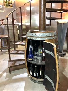 a wooden barrel with bottles in it sitting on the floor next to some chairs and tables