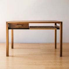 a wooden table with two drawers on top and one drawer at the bottom, sitting on a hard wood floor