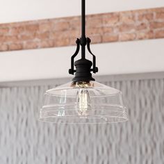 a clear glass light fixture hanging from a ceiling in a room with brick wallpaper