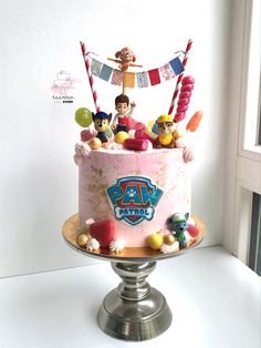 a birthday cake decorated with toy figures and decorations on a table in front of a window