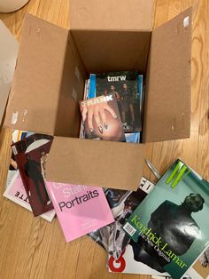 a cardboard box filled with books on top of a wooden floor