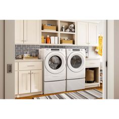 a washer and dryer in a small room with white cupboards on the wall