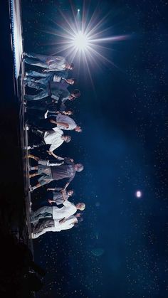 group of people standing in line on stage with bright light shining down from the sky