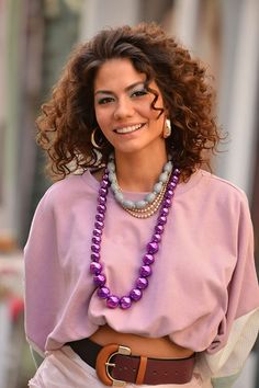 a woman wearing a purple shirt and some beads