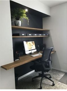 a desk with a computer on top of it next to a plant and bookshelf