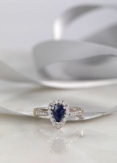 an engagement ring with a pear shaped blue sapphire