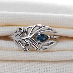 Sterling Silver Statement Topaz Ring Peacock Feather design with an eye set with a natural African blue pear topaz. The ring is an adjustable design - please see images. Small is best suited for adjustment between a size I-N (US size 5 - 7), Large is adjustable M -T (US size 6.5 - 10) Topaz are associated with love, self esteem and good fortune. They are the birthstone for December. Finished with a commercial grade rhodium plate to give a high quality shine finish. Supplied in an Ojewellery pres Krishna Ring Design, Pacchala Haram, Krishna Ring, Peacock Feather Jewelry, Peacock Feather Ring, Silver Anklets Designs, Peacock Feather Design, Topas Ring, Peacock Ring