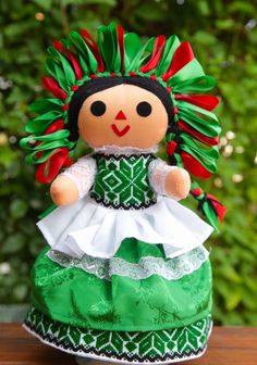 a green and white doll sitting on top of a wooden table