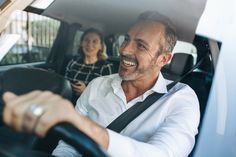 a man driving a car with a woman in the back seat and another person behind him