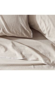 an unmade bed with white linens and pillows on top of each pillowcase