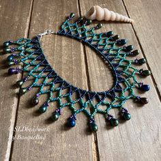 a necklace made with beads and shells on a wooden table next to a seashell