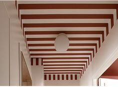 an empty hallway with red and white stripes on the ceiling, and a round light fixture hanging from the ceiling