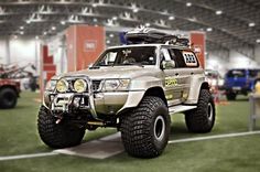 an off - road vehicle on display in a large building with other vehicles around it