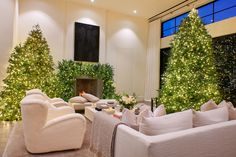 a living room filled with white furniture and christmas trees