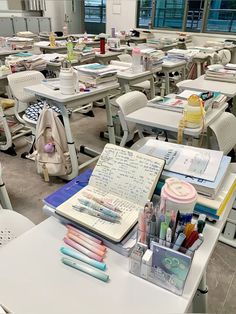 an empty classroom with many desks and writing materials on them, including notebooks