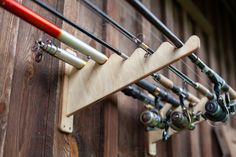 there are many fishing rods attached to the wooden wall with hooks on each rod and two different types of lures hanging from it