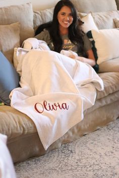 a woman sitting on top of a couch covered in white blankets with the word claudia written on it