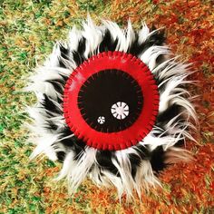 a red and black frisbee with white feathers on it sitting in the grass