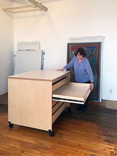 a woman standing in front of a desk with a drawer on the bottom and an open file cabinet below