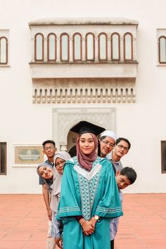 a group of people standing in front of a building with a woman wearing a headscarf