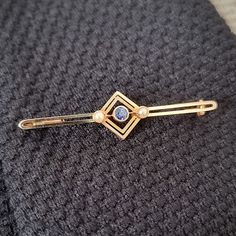 A delightful late Edwardian to Art Deco era bar brooch, crafted in 15ct yellow gold and set with a central round sapphire, with a small seed pearl set to either side, in a open square setting. An elegant vintage piece which looks superb pinned to a jacket, blouse or tie. Circa 1910-1920. Stamped as 15ct gold, with a 9ct gold (tested) pin. The brooch measures approximately 47.1mm (L) x 11.5mm (W) x 4.3mm (D). The approximate weight is 2.8 grams. CONDITION: In very good antique condition, with som Engraved Cross, Bar Brooch, Wedding Band Engraving, Jacket Blouse, Round Sapphire, Pearl Cluster, Gold Engraving, Pearl Set, Art Deco Era