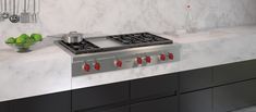 a stove top oven sitting inside of a kitchen next to a bowl of green apples