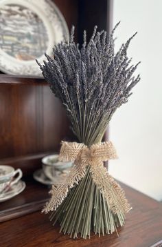 a bunch of dried lavenders sitting on top of a wooden table next to a cup and saucer