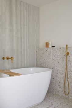 a white bath tub sitting next to a walk in shower under a faucet