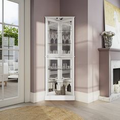 a tall white cabinet with glass doors in a living room next to a fire place